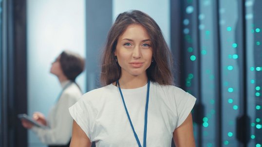 IT Frau steht im Serverraum und schaut in die Kamera IT Frau steht im Serverraum und schaut in die Kamera